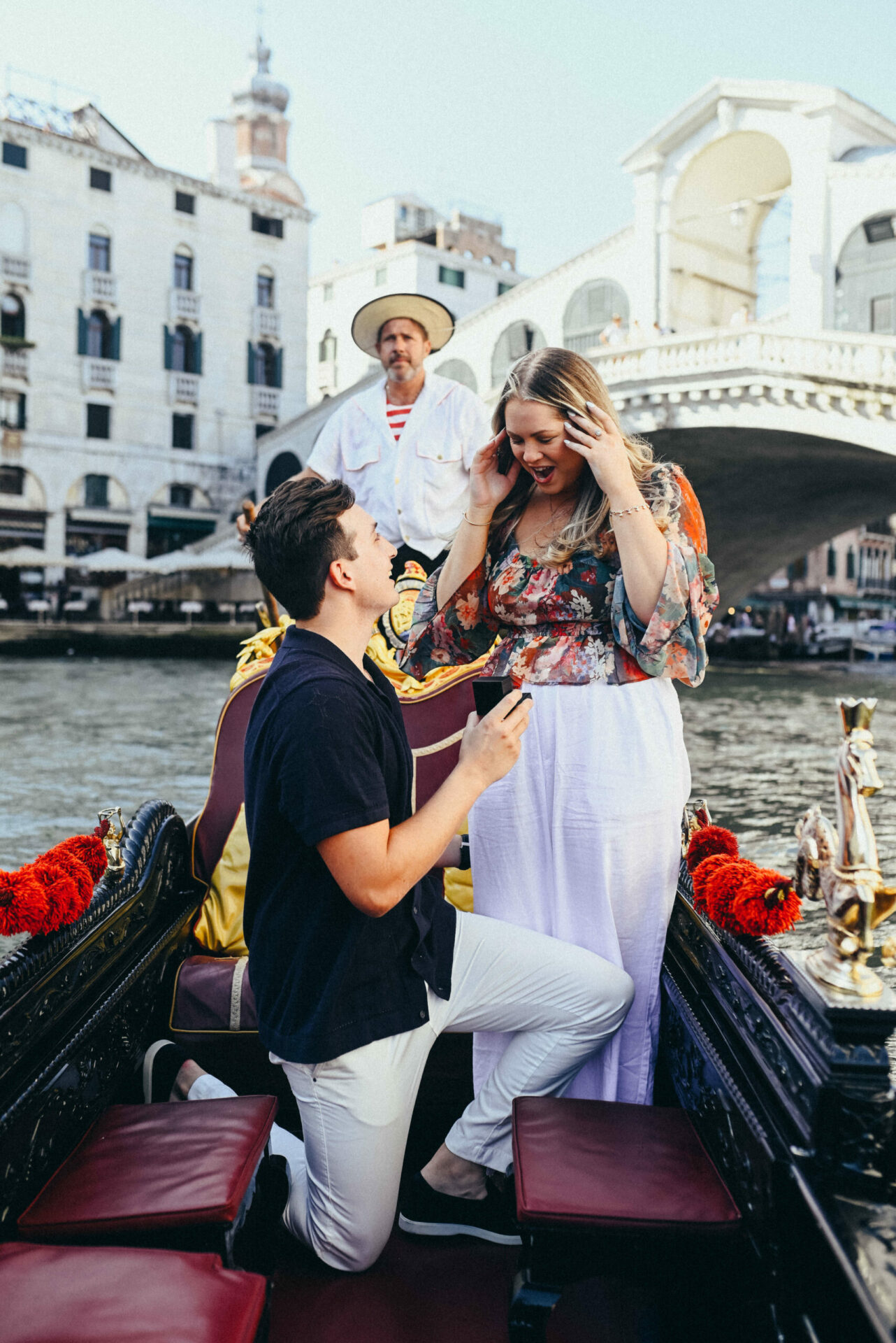 man proposing to a woman on a gondola ride in front of rialto bridge in venice